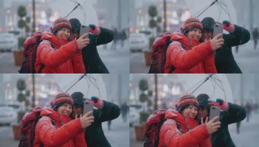冬天的城市里，年轻的女游客用智能手机和当地人自拍高清在线视频素材下载