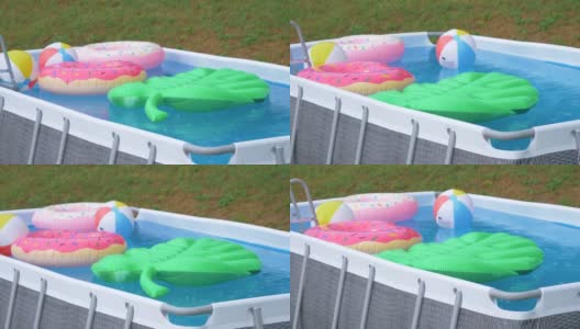 在夏天的暴雨中，后院的小游泳池里装满了五颜六色的漂浮物。高清在线视频素材下载