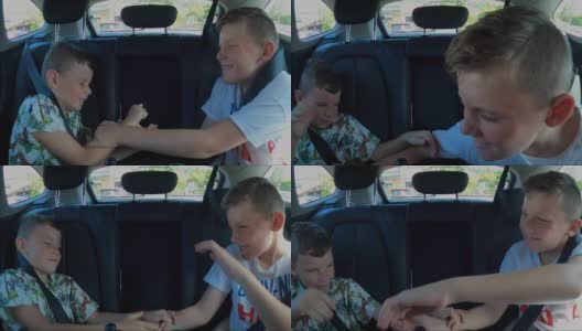 两个淘气的小男孩在一辆汽车的后座上互相碰触和骚扰，又打又缩。战斗随着双腿即将开始踢腿而升级。高清在线视频素材下载