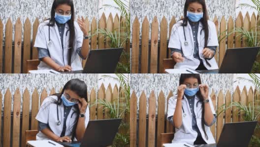 印度女医生坐在笔记本电脑前。在医院工作的压力性头痛，由于印度冠状病毒病例的增加而感到压力。劳累过度的医生。高清在线视频素材下载