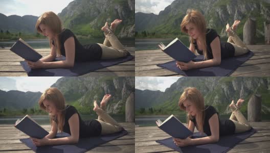 一个年轻女子在山中的湖边看书高清在线视频素材下载