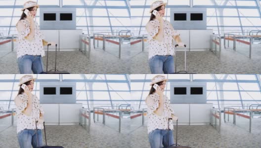 女性旅客站在机场候机楼拿着行李箱打手机高清在线视频素材下载
