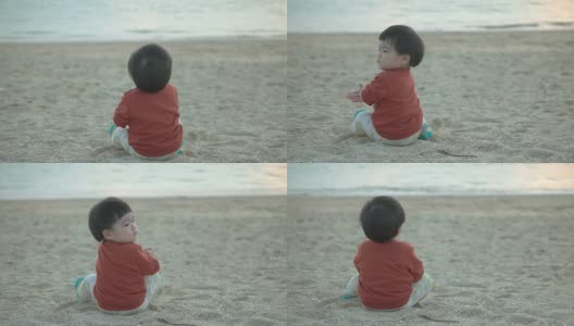 婴儿坐在海滩上。高清在线视频素材下载