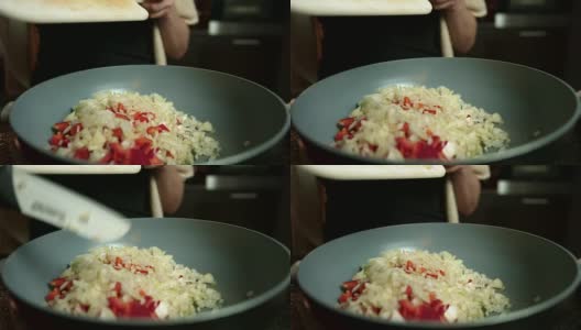 特写慢镜头的手加入切碎的洋葱和红辣椒在煎锅烹饪一顿饭高清在线视频素材下载