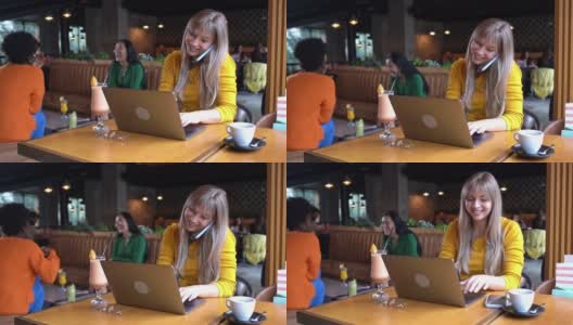 忙碌的女性自由职业者，在现代化的自助餐厅里，一边在笔记本电脑上工作，一边用手机聊天，一心多用高清在线视频素材下载