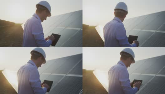 日落时分，一名年轻的工程师正在用平板电脑检查太阳能光伏板场地的阳光和清洁情况。理念:可再生能源、技术、电力、服务、绿色、未来高清在线视频素材下载