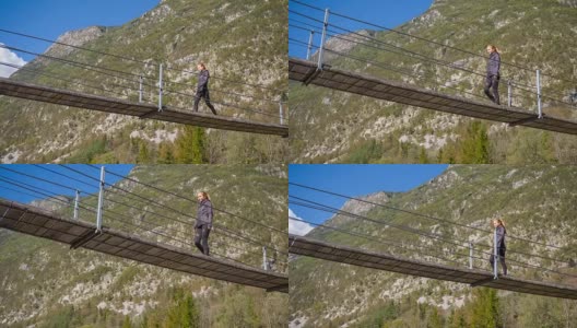 一名年轻女子正穿过山腰上的一座木制吊桥高清在线视频素材下载