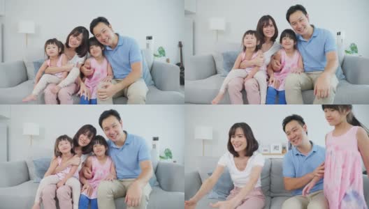 亚洲幸福家庭的肖像，花时间与孩子一起在家里。年轻可爱的小女孩和父母坐在沙发上微笑，看着客厅里的镜头。活动关系的概念高清在线视频素材下载