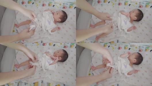 快乐的亚洲家庭母亲打扮新生婴儿(0-1个月)男婴。高清在线视频素材下载