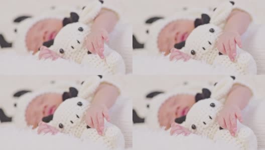 亲密的手快乐的新生婴儿穿着可爱的奶牛服装躺着睡觉拥抱奶牛娃娃在白色的背景舒适和安全。可爱的亚洲婴儿在婴儿床上睡觉和打盹高清在线视频素材下载