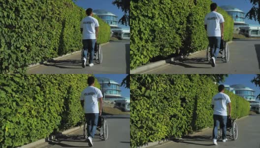 一个仁慈的志愿者推着轮椅的后视图高清在线视频素材下载