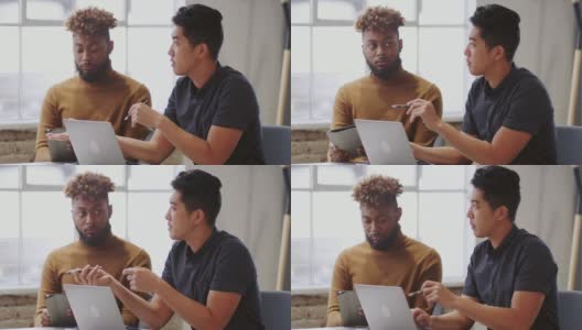 两名男性创意人员正在用笔记本电脑和平板电脑与一位看不见的同事开会高清在线视频素材下载
