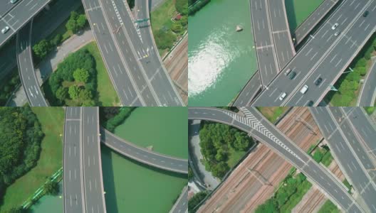 在阳光明媚的日子里，从空中俯瞰高速公路立交桥的多层交叉路口，快速移动的汽车被绿树环绕，河边有一条河。高清在线视频素材下载