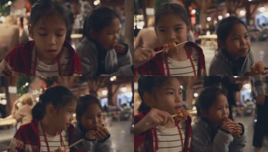 亚洲姐弟小女孩在泰国夜市街头小吃吃热狗美味的街头小吃。高清在线视频素材下载
