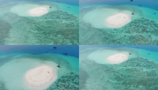 无人机飞过白色沙滩和蓝绿色海水的圆形沙洲，马尔代夫达拉万胡。只有一艘船和两个人被困。高清在线视频素材下载