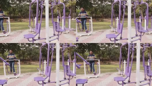 平移镜头，健力士步行者机，年轻人在公园户外健身步行者机上锻炼高清在线视频素材下载