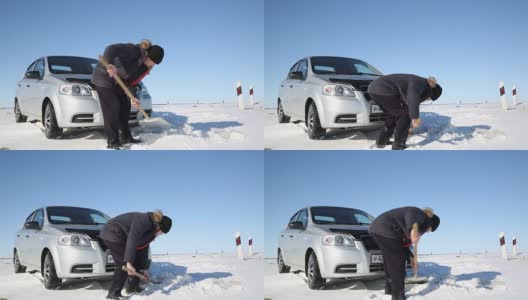 司机用铲子把汽车从雪中挖出来。高清在线视频素材下载