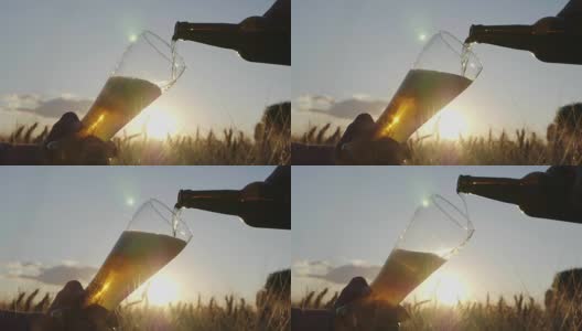把啤酒从瓶子里倒进玻璃杯里。在日落时分的麦田里。慢动作视频高清在线视频素材下载