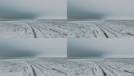 一辆黑色汽车行驶在雪地里的乡村道路上，无人机拍摄的鸟瞰图高清在线视频素材下载