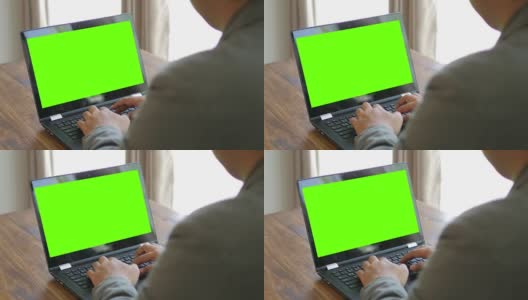 商人用绿色屏幕的笔记本电脑键盘打字，摄影车从右向左拍摄高清在线视频素材下载