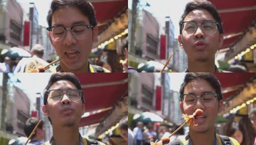 日本东京，一名游客在筑地鱼市吃烤章鱼。高清在线视频素材下载