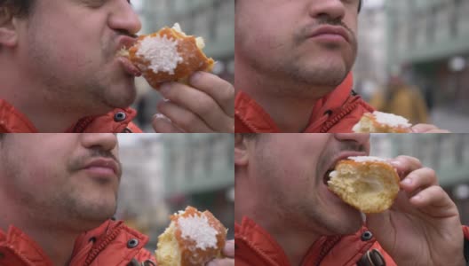 一名男子在城市街道上吃传统的波兰甜甜圈高清在线视频素材下载