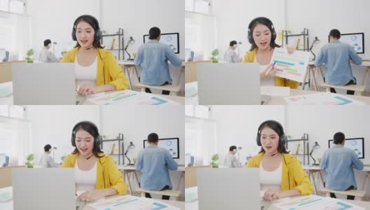 亚洲商界女性在新常态下保持社交距离以预防病毒，同时在办公室使用笔记本电脑向同事演示视频通话计划。高清在线视频素材下载