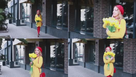 一个金发碧眼的白人女孩，穿着一件带有圆点图案的裙子，一件黄色的外套，戴着一顶红色的贝雷帽，神情激动地沿着堤岸走着，欣赏着一束黄色的郁金香高清在线视频素材下载