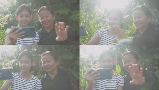 亚洲可爱的十几岁女孩和她的奶奶喜欢在家里的后院用手机视频聊天，一边挥手一边和家人聊天。高清在线视频素材下载