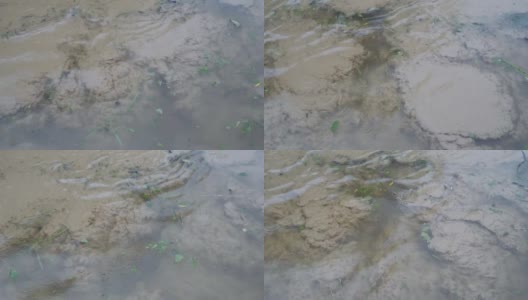 在阴天下雨的时候，淤泥、泥沙和沙子从底部漂浮在水面上沸腾的水面的顶部视图。坏天气。环境污染。特写镜头。4 k。高清在线视频素材下载