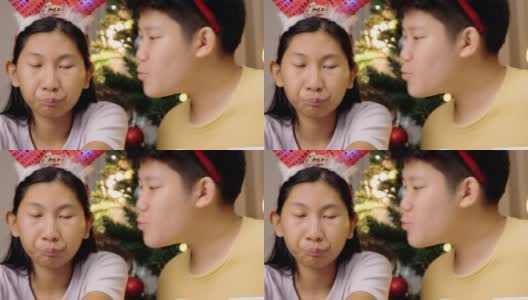 男孩亲吻他的妹妹与圣诞树装饰背景在家里，生活方式的概念。高清在线视频素材下载