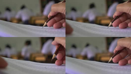 教育考试概念:高中课堂上，学生手持考笔，写答题卡或练习题，在木桌上用复写纸电脑答题高清在线视频素材下载