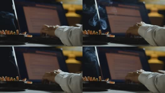一个男人在笔记本电脑上工作，在一个装满烟头的烟灰缸上抽烟高清在线视频素材下载