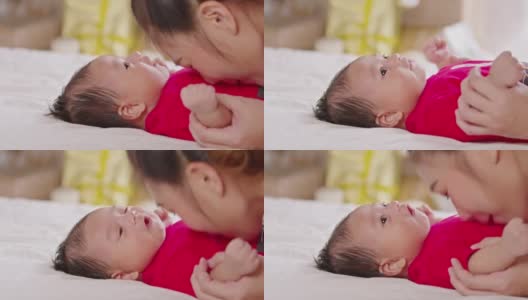 美丽迷人的亚洲妈妈亲吻宝宝的肚子甜美可爱。快乐的妈妈和宝宝一起看着宝宝，微笑着爱。母亲和新生儿概念高清在线视频素材下载