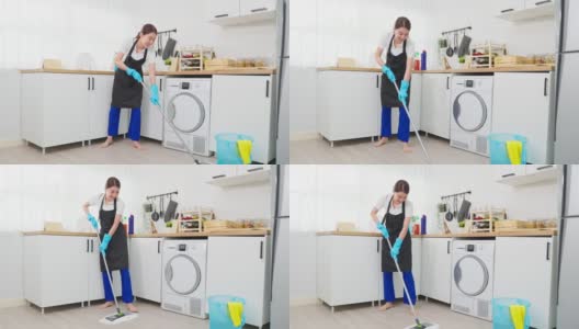 亚洲主动清洁服务女工清洁厨房和家庭。美丽的年轻女孩管家清洁工感到高兴，在地板上拖地工作，家务或家务在家里。高清在线视频素材下载