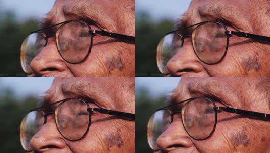 一位戴着眼镜的老人的特写脸，在阳光下眺望远方。眼光和老年人的观念高清在线视频素材下载