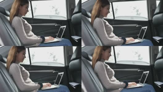 年轻女子在车里用笔记本电脑打字高清在线视频素材下载
