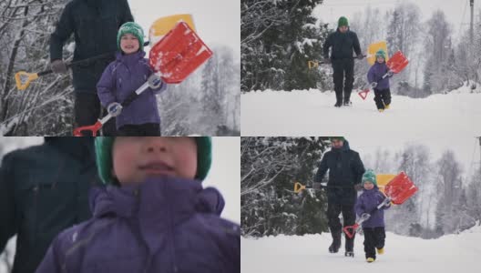 父亲和儿子在暴风雪中拿着雪铲对着摄像机在乡村公路上奔跑。高清在线视频素材下载