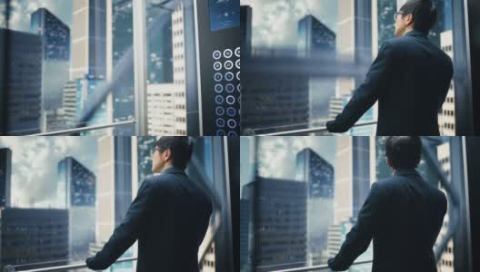 时尚的日本商人乘坐玻璃电梯到现代商务中心的办公室。从电梯的全景窗口看现代市中心的摩天大楼。转身对着镜头。高清在线视频素材下载