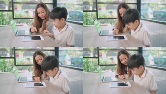夏天的时候，女商人坐在孩子旁边教孩子做作业。男孩笑着看着平板电脑。在学习过程中感到快乐。教育和周末观念。高清在线视频素材下载