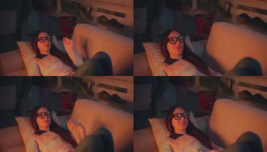 美丽的女人躺在沙发上的肖像和使用智能眼镜。元境智能眼镜虚拟现实技术概念高清在线视频素材下载