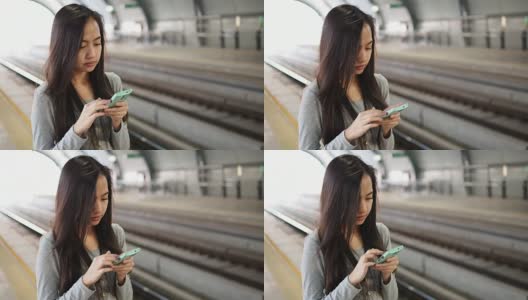 一名女子在等火车时使用智能手机高清在线视频素材下载