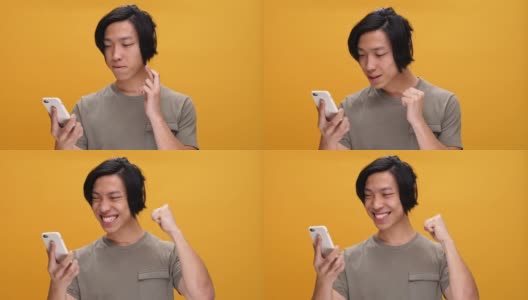 年轻快乐的亚洲人用手机做赢家手势高清在线视频素材下载