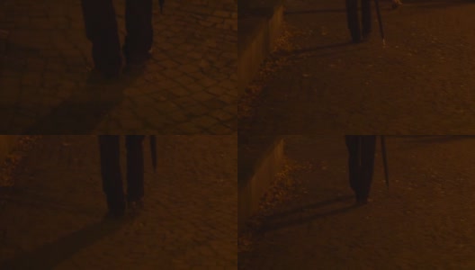 一个男人撑着伞走在人行道上，两脚沐浴在黑暗中高清在线视频素材下载