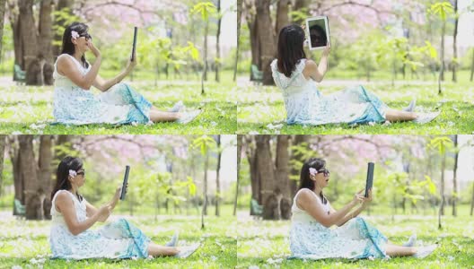 一个女人在花园里用平板电脑和朋友聊天高清在线视频素材下载