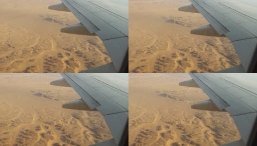 飞机飞过沙漠，从飞机机翼上的舷窗和襟翼上看到的景象。高清在线视频素材下载