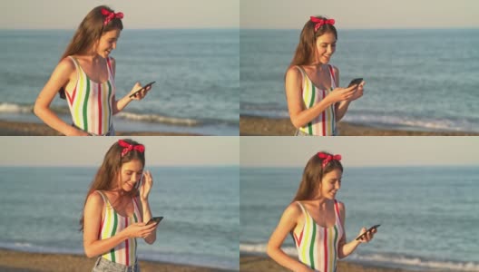 漂亮的女人戴着红色的发带和条纹泳衣，用她的智能手机高清在线视频素材下载