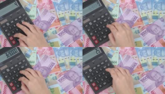 计数在一个计算器上的成堆的印尼钱高清在线视频素材下载