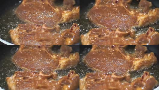 色彩斑斓:多汁的猪肉排在煎锅里煎。高清在线视频素材下载