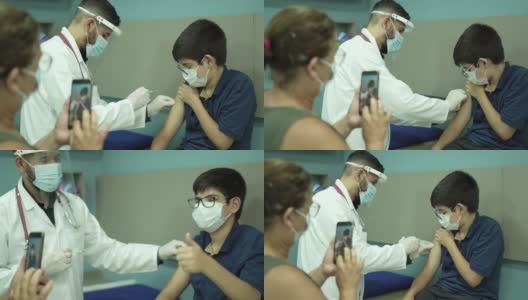 母亲在儿子接种新冠肺炎疫苗时给他拍照高清在线视频素材下载